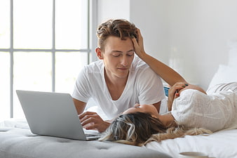 Young couple relaxing on bed with laptop
