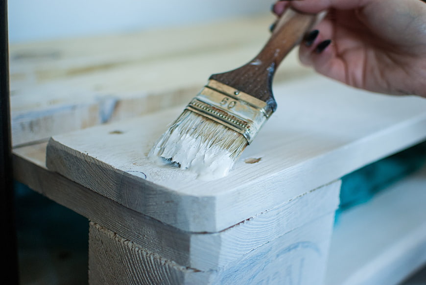 Hand Applying White Paint To Wood With Brush