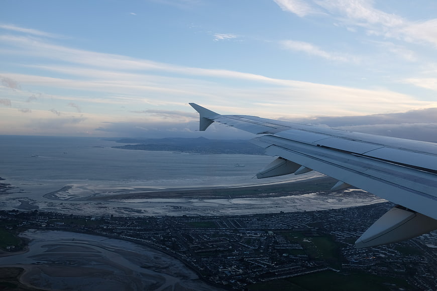 Airplane Wing Over Coastal City and Ocean