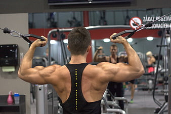 Muscular man performing cable fly exercise in a modern gym
