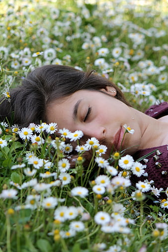 Woman sleeping peacefully in a field of white daisies