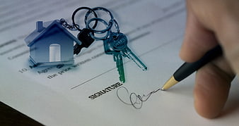 Hand signing real estate contract with house keychain and keys