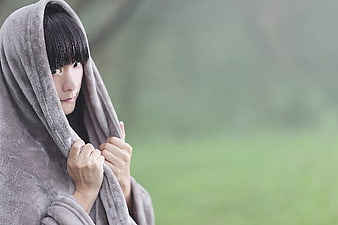 Woman wrapped in gray blanket outdoors with copy space