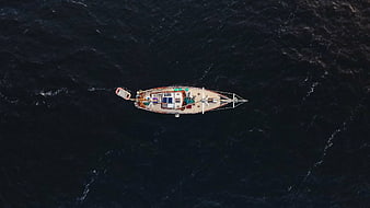 Aerial top-down view of sailboat on dark ocean