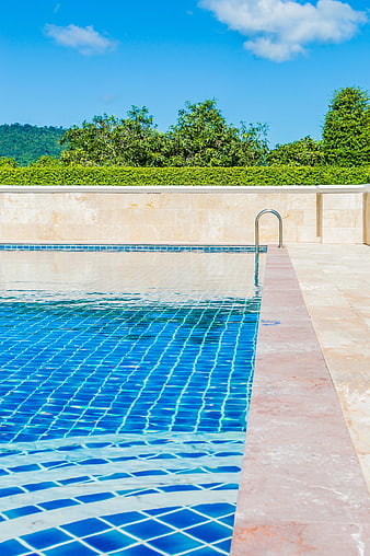 Luxury outdoor swimming pool with blue tiles and stone deck