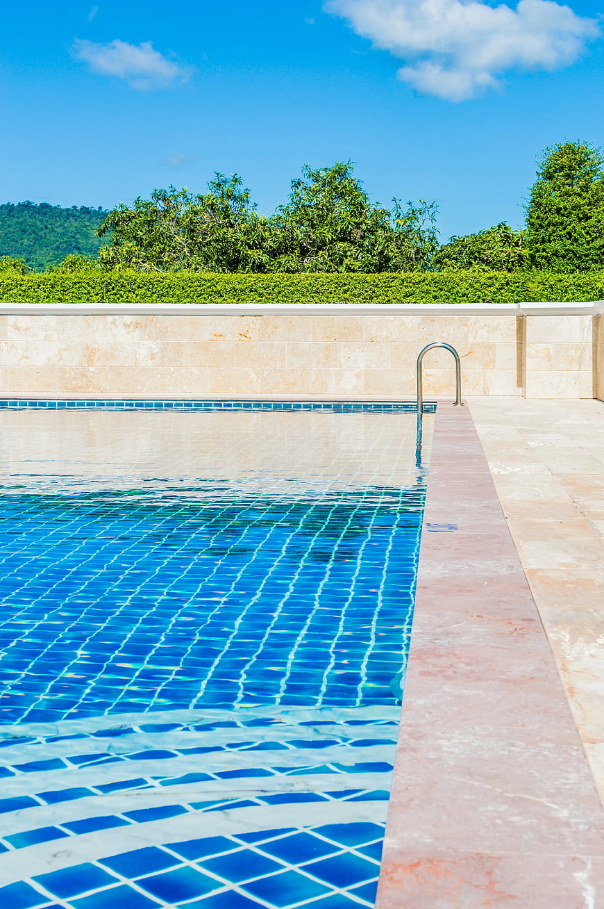 Luxury outdoor swimming pool with blue tiles and stone deck