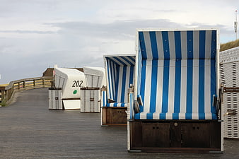 Blue and white striped beach chairs on a wooden pier