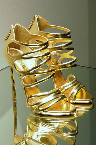 Elegant Gold Strappy High Heels on Reflective Surface