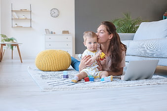 Mother Playing With Baby Son And Laptop In Living Room
