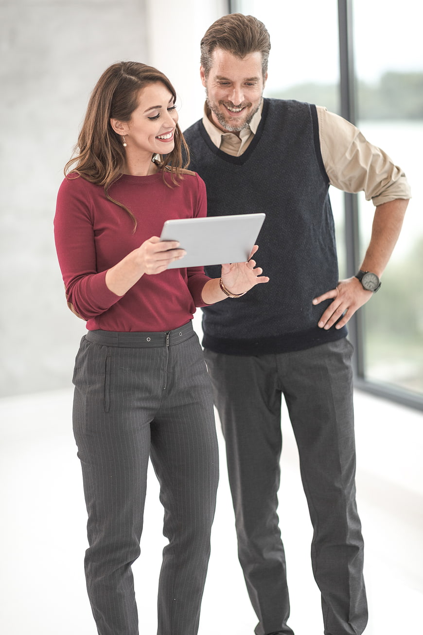 Happy business couple using tablet in modern office