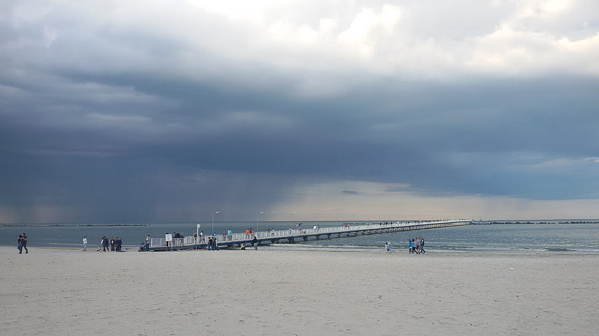 Dramatic storm clouds over a beach pier with people