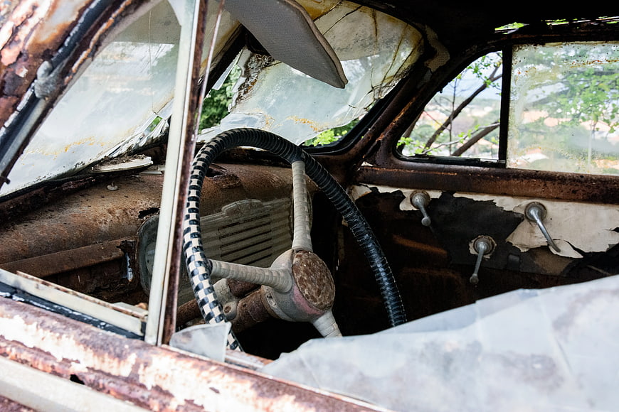Rusty vintage car interior with broken windshield and steering wheel