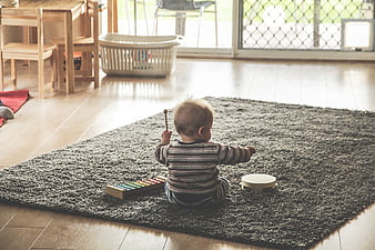 Baby playing xylophone and tambourine on rug