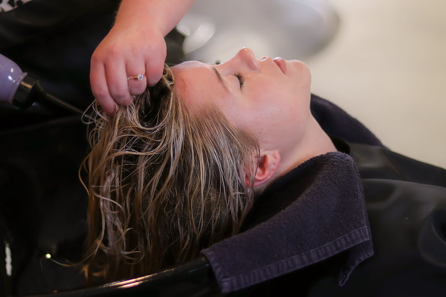 Woman relaxing at hair salon during shampoo treatment