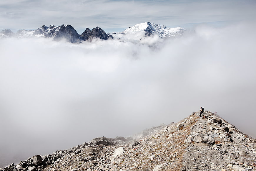 Hikers on Rocky Mountain Ridge Above Sea of Clouds