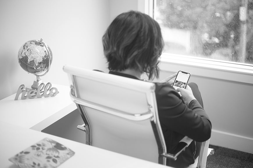 Woman using smartphone in office by window