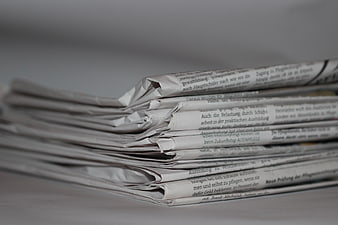 Stack of folded newspapers with German text on gray background