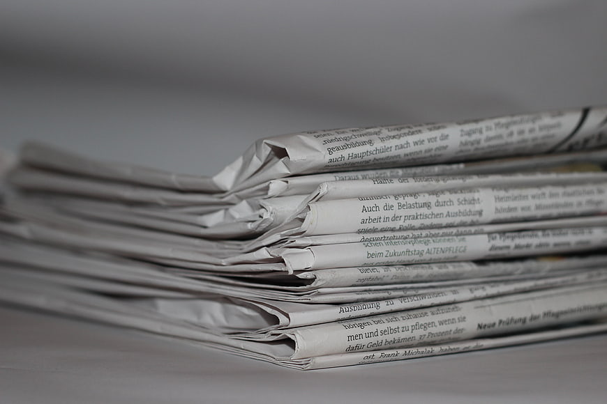 Stack of folded newspapers with German text on gray background