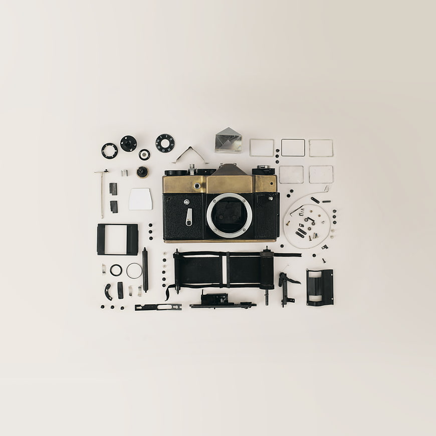 Disassembled vintage camera parts flat lay on white background
