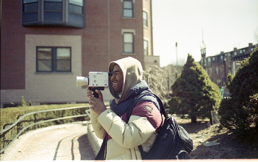 Man Filming with Vintage Camera in Urban Setting