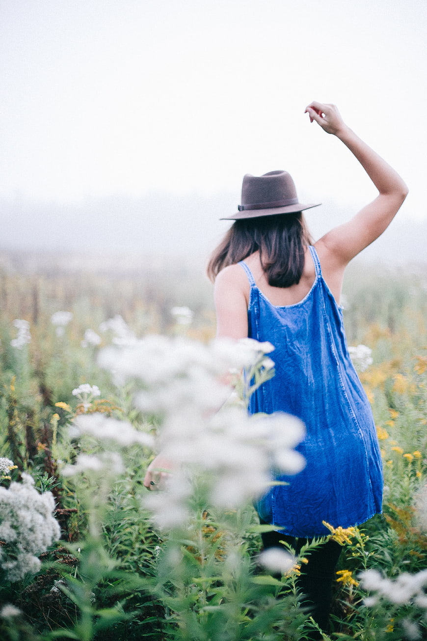 Woman in Blue Dress and Hat in Wildflower Field