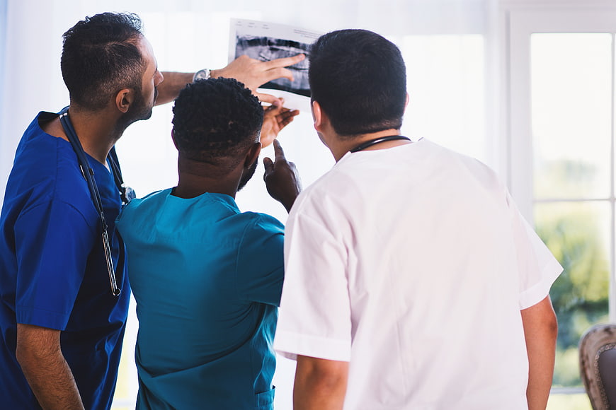 Diverse medical team analyzing x-ray film in hospital