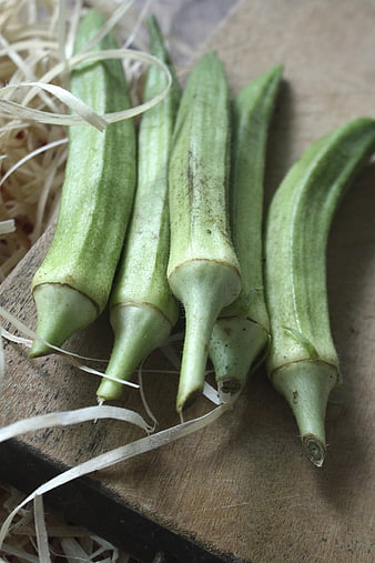 Fresh Green Okra Pods on Wooden Board with Straw