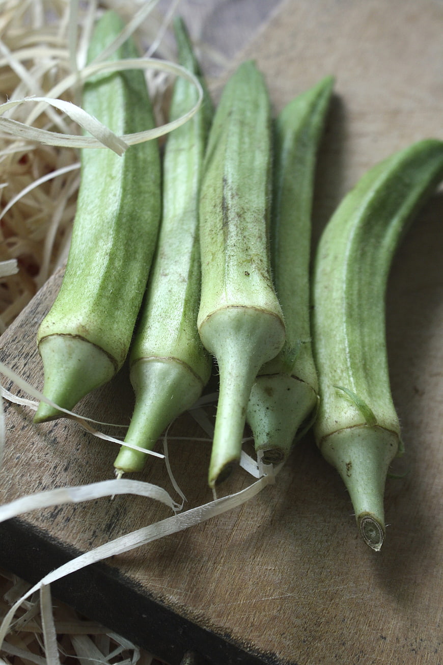 Fresh Green Okra Pods on Wooden Board with Straw