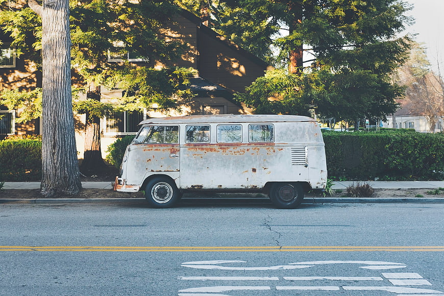 Vintage Rusty White VW Bus Parked on Street