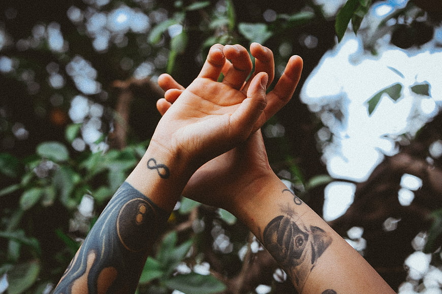Tattooed Hands Reaching Up in Nature