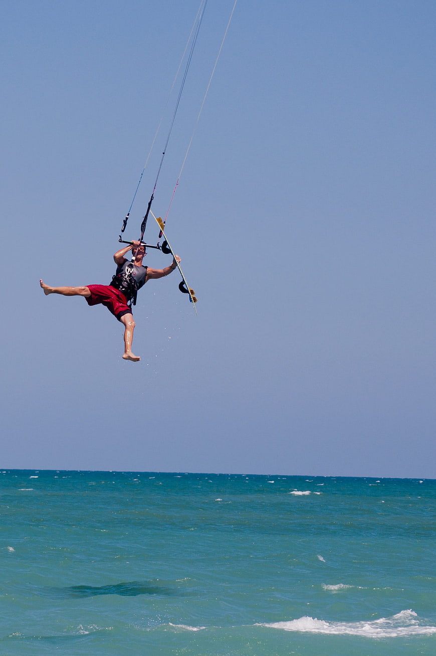 Kitesurfer Jumping High Over Turquoise Ocean Waves