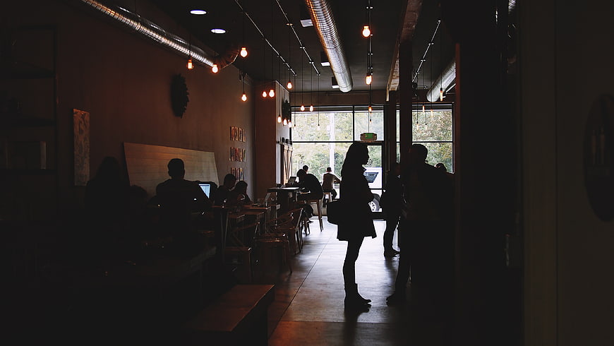 Silhouettes of people working in a dimly lit modern cafe