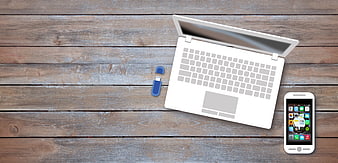 Flat lay of laptop, smartphone, and USB drive on wooden desk