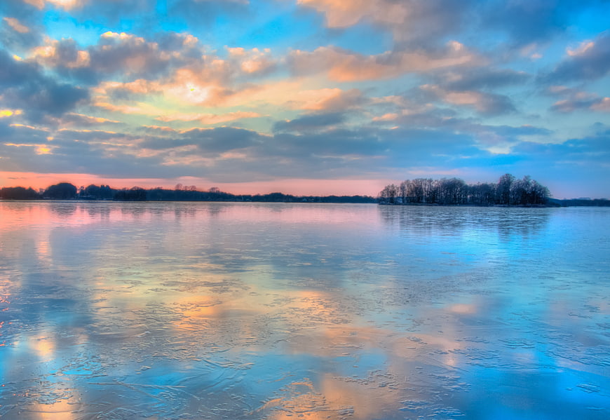 Colorful sunset reflection on frozen icy lake landscape