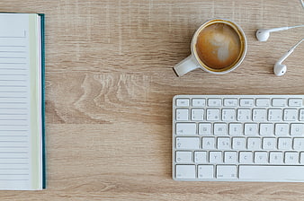Flat lay workspace with coffee, keyboard, notebook, and earphones