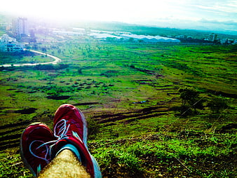 Red running shoes resting on grassy hill overlooking landscape