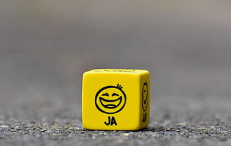 Yellow Smiley Dice With JA Label On Concrete Surface