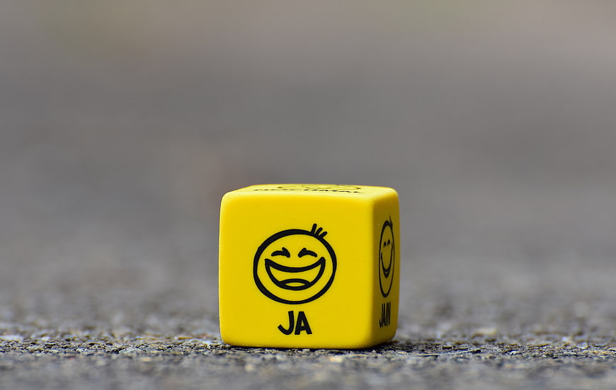 Yellow Smiley Dice With JA Label On Concrete Surface