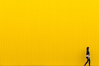 Woman Walking Past Vibrant Yellow Corrugated Wall