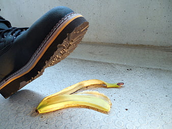 Black boot about to slip on banana peel on concrete