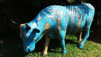 Colorful painted cow sculpture with cityscape art in garden