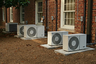 Row of outdoor air conditioning units against brick building
