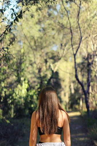 Woman with long hair walking away on forest path