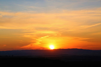 Vibrant Orange Sunset Over Silhouetted Mountain Range