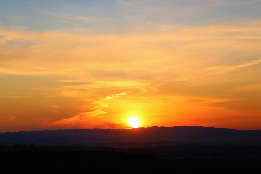Vibrant Orange Sunset Over Silhouetted Mountain Range