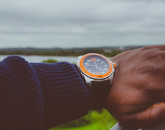 Man wearing orange dive watch on wrist outdoors