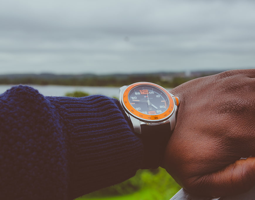 Man wearing orange dive watch on wrist outdoors