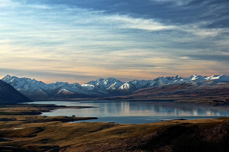 Snow-Capped Mountains Reflected in Calm Lake at Sunset