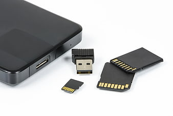 Black external hard drive, USB flash drive, and memory cards on white background