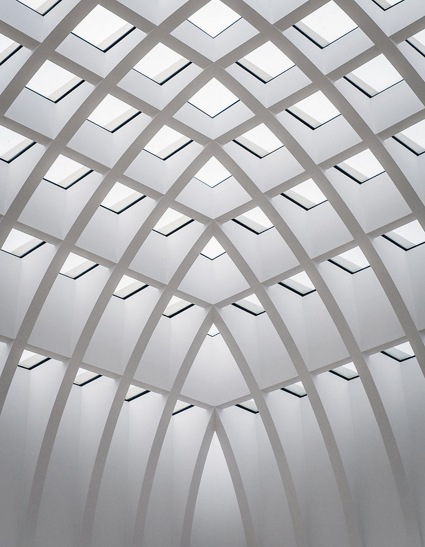 Modern white vaulted ceiling with skylights and geometric arches